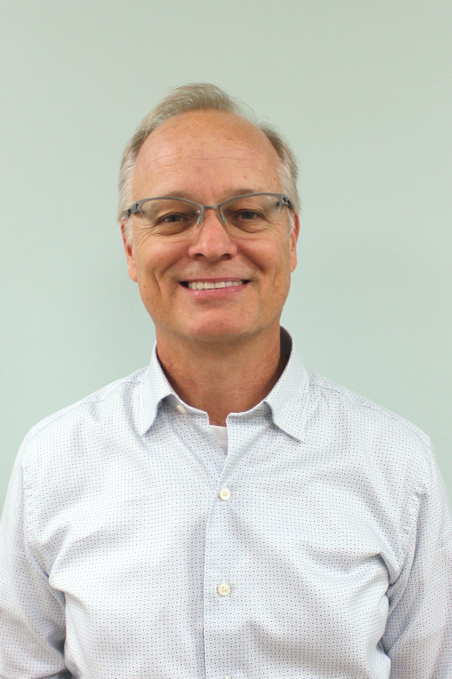 Senior man smiling wearing glasses and white shirt
