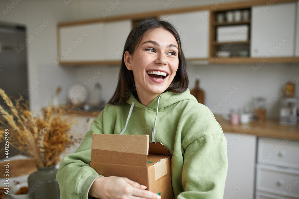 "happy woman holding delivery box in kitchen"